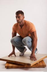 Kneeling pose orange thsirt light blue jeans of bodybuilder Harold